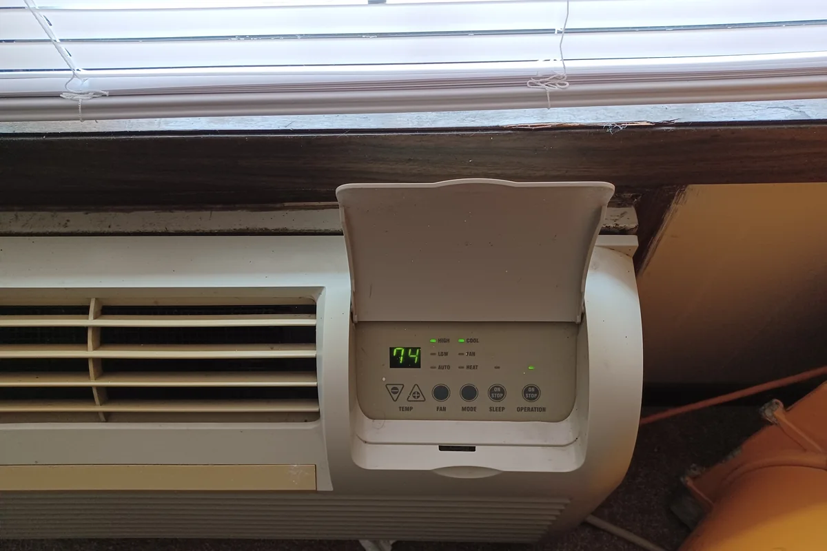 A packaged terminal air conditioner installed in a residential apartment, representing a common through-wall system.
